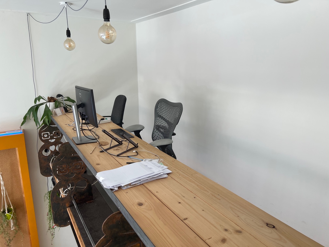 De flexplekken: een lange houten tafel met beeldschermen en bureaustoelen onder hanglampen.
