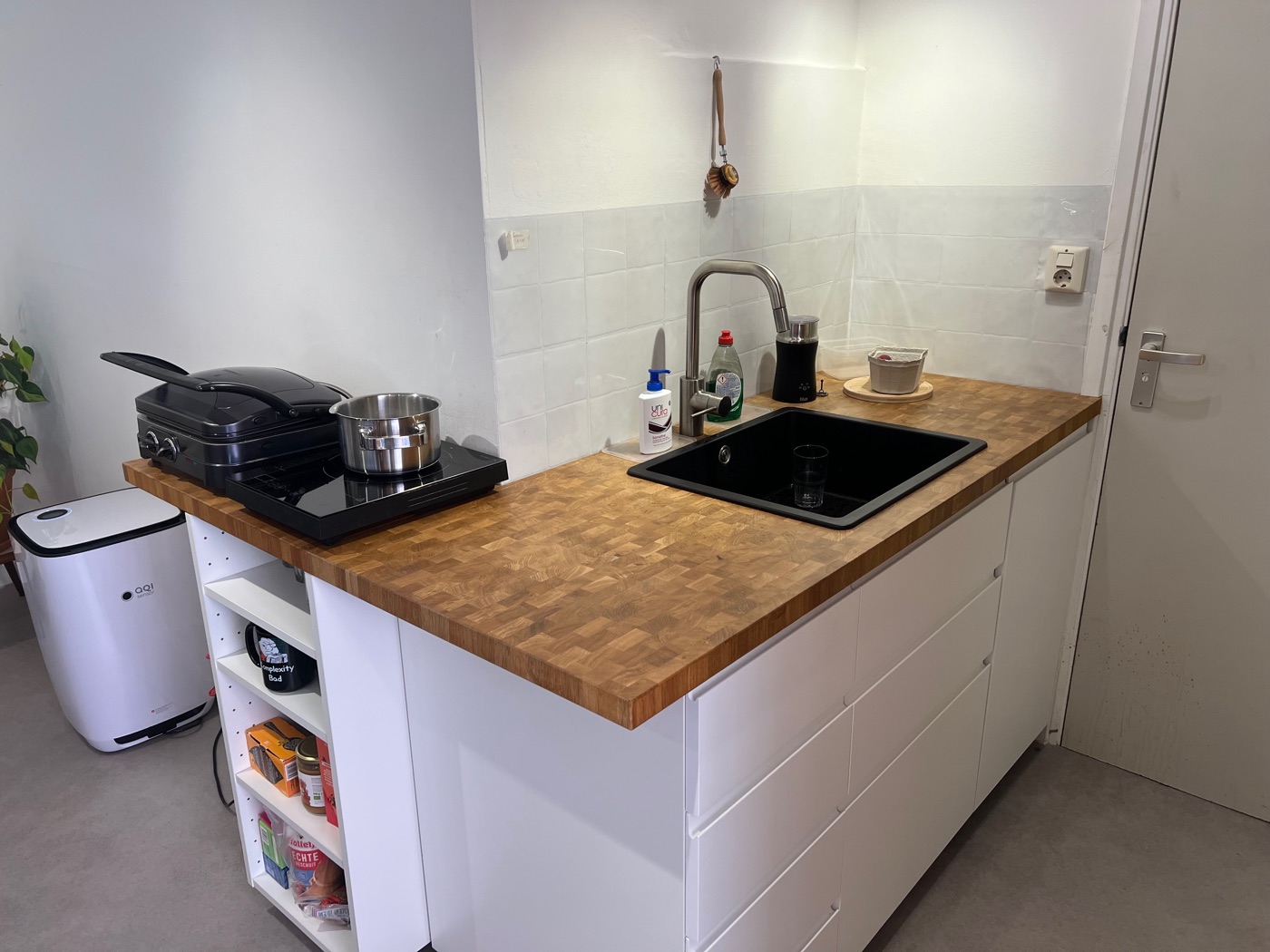 De keuken: een houten aanrechtblad met spoelbak, inductiekookplaat en tosti-apparaat.